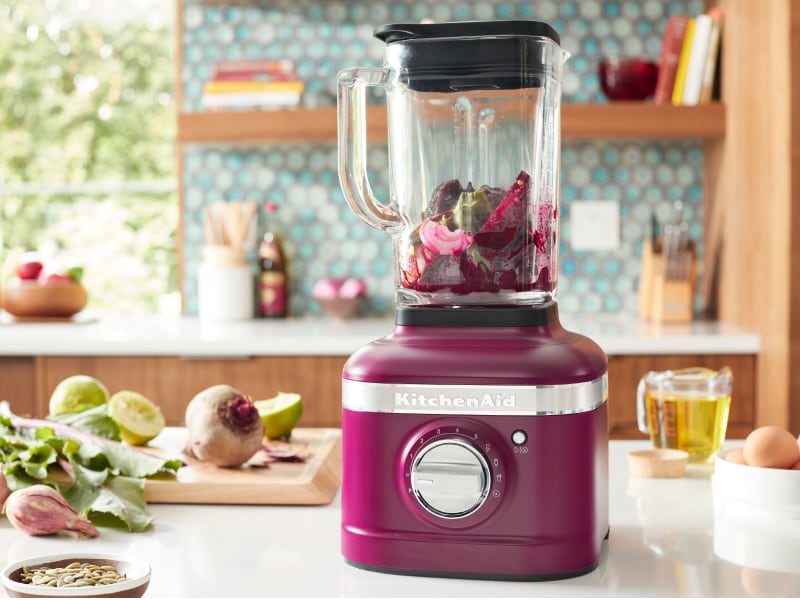 A KitchenAid® blender with fresh vegetables in a modern kitchen. A KitchenAid® blender with fresh vegetables in a modern kitchen.