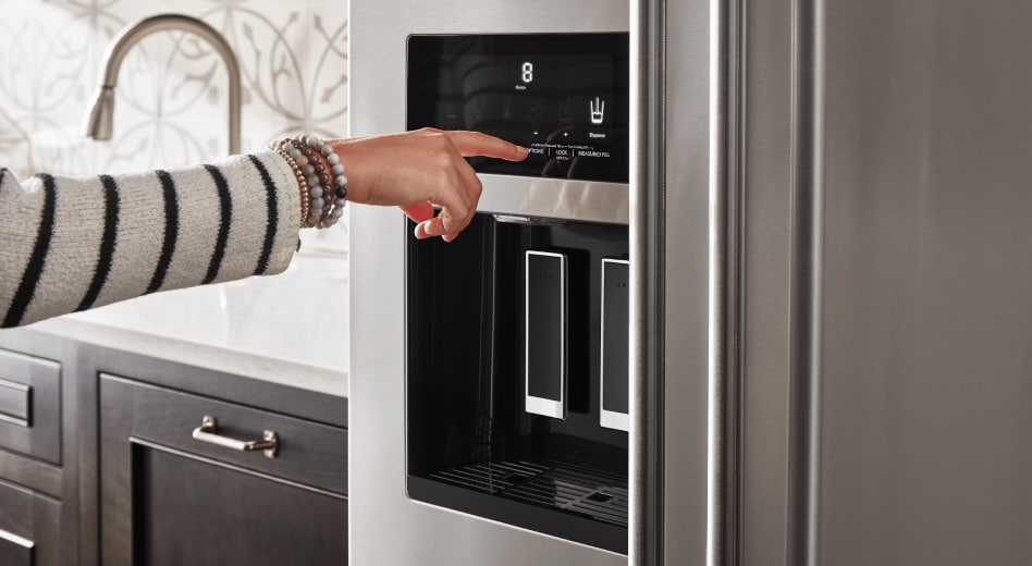 Finger touching the control pad of a refrigerator water dispenser Finger touching the control pad of a refrigerator water dispenser