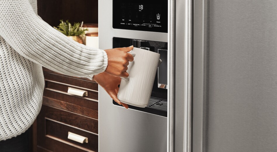 Woman filling a container with water from a refrigerator Woman filling a container with water from a refrigerator