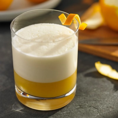 A glass of an orange whiskey cocktail