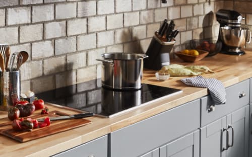 Sliced vegetables next to a black KitchenAid® induction cooktop.