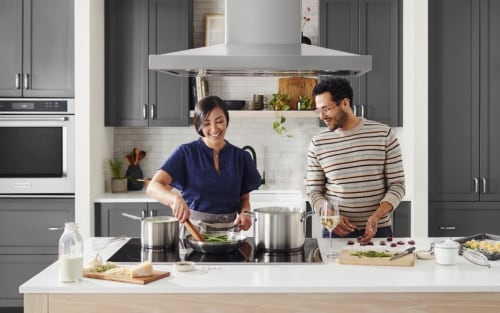 Two people cooking at an island