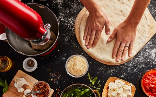 Person kneading stretching next to a KitchenAid® stand mixer