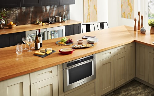 A KitchenAid® microwave drawer below a counter with various food items.