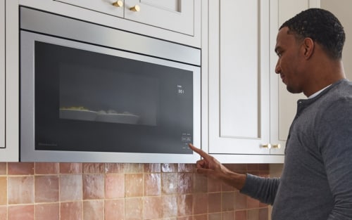 Person selecting settings on an over-the-range microwave