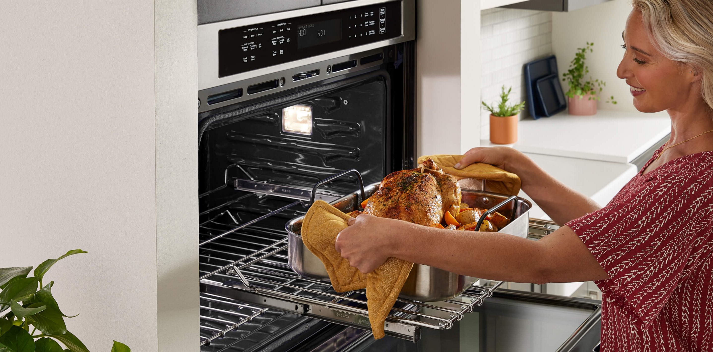 A person pulling a roasting pan out of the oven.